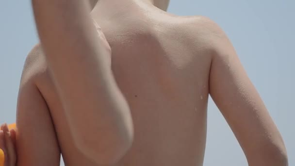 Moeder toepassing van zonnebrand Lotion op strand — Stockvideo