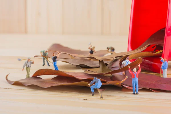 Immagine di mini figura bambole lavoratore raccogliere foglie secche nel re — Foto Stock