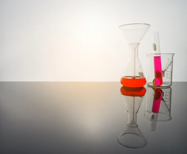 Lab glassware on glass table in warm tone. — Stock Photo, Image