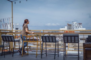 Kahve barının çatısında oturan kadınlar, gündüz kasaba binasını görüyorlar..