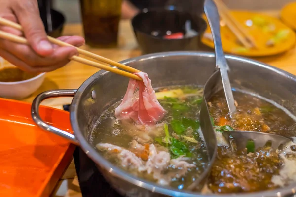 韓国のしゃぶしゃぶ店でお椀の上に箸で豚肉をスライスしたイメージ — ストック写真