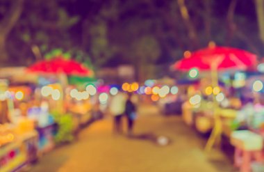 Şenlik ışıklarıyla dekore edilmiş arka plandaki bulanık gece pazarının görüntüsü. (Klasik ton))