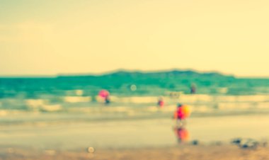 Arka plan kullanımı için sahilde yürüyen bulanık insanların soyut görüntüsü. (Klasik ton))