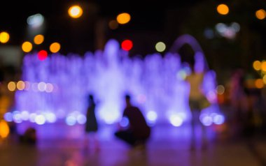 Fıskiyeye gece lambasıyla bakan insanların bulanık arkaplan görüntüsü .