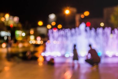 Fıskiyeye gece lambasıyla bakan insanların bulanık arkaplan görüntüsü .