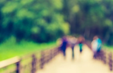 Arka plan kullanımı için yeşil bahçeye açık alanda yürüyen bulanık insanların görüntüsü. (Klasik ton))