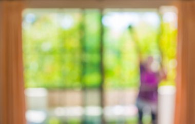 Arka plan kullanımı için evdeki pencereleri temizlerken ev bekçisinin bulanık görüntüsü .