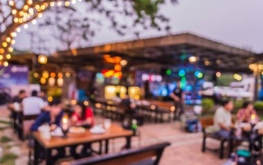 Arka plan kullanımı için akşam vakti açık hava restoranındaki bulanık insanların görüntüsü. (Klasik ton))