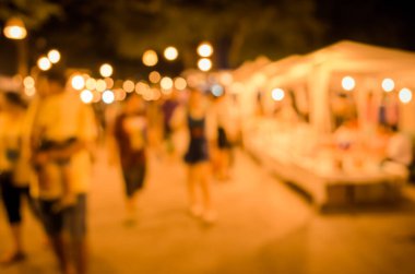 Şenlik ışıklarıyla süslenmiş caddedeki bulanık arka plan gece pazarının görüntüsü .