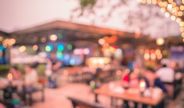 Arka plan kullanımı için akşam vakti açık hava restoranındaki bulanık insanların görüntüsü. (Klasik ton))