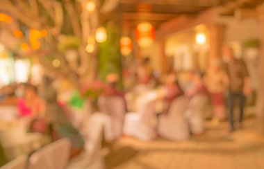 Düğün, akşam yemeği ya da festival etkinliği için hazırlanmış arka plan kullanımı için büyük salonun içindeki güzel ışıklandırma dekorasyonlu büyük yemek masasının soyut bulanık görüntüsü. (Klasik ton))