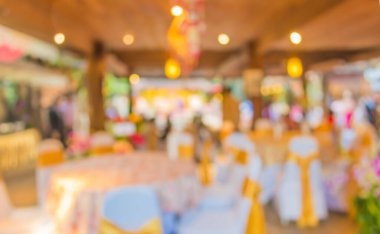 Düğün, akşam yemeği ya da festival etkinliği için hazırlanmış arka plan kullanımı için büyük salonun içindeki güzel ışıklandırma dekorasyonlu büyük yemek masasının soyut bulanık görüntüsü .