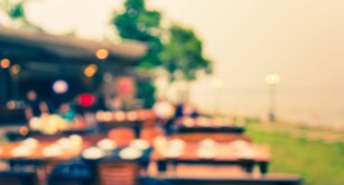 Arka plan kullanımı için akşam vakti açık hava restoranındaki bulanık insanların görüntüsü. (Klasik ton))