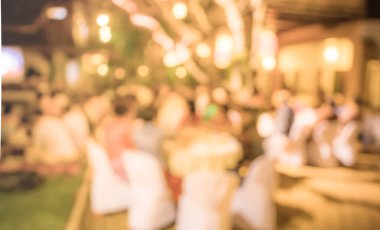 Düğün, akşam yemeği ya da festival etkinliği için hazırlanmış arka plan kullanımı için büyük salonun içindeki güzel ışıklandırma dekorasyonlu büyük yemek masasının soyut bulanık görüntüsü. (Klasik ton))