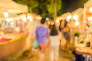Gece pazarındaki bulanık arka plan insanlarının görüntüsü festival ışıklarıyla süslenmiş. .
