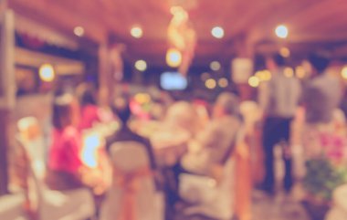 Düğün, akşam yemeği ya da festival etkinliği için hazırlanmış arka plan kullanımı için büyük salonun içindeki güzel ışıklandırma dekorasyonlu büyük yemek masasının soyut bulanık görüntüsü. (Klasik ton))