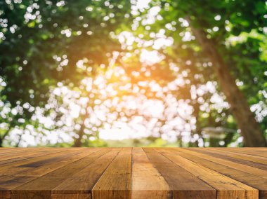 Ahşap masa ve arka plan kullanımı için güneşli yeşil ağaçların bulanık görüntüsü. (Klasik ton))