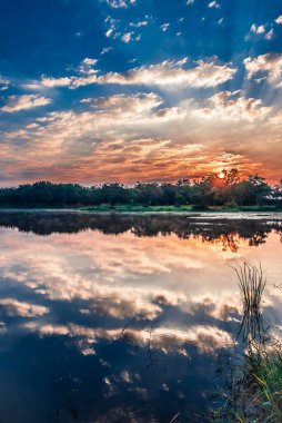 Gölü ve çimlerin dikey HDR görüntüsü ve sabah saatinde gün doğumu.