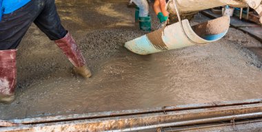 İnşaat alanında zemine beton döken işçilerin görüntüsü.