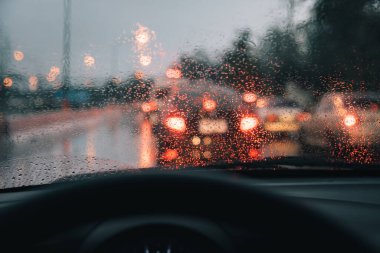Akşam vakti araba kullanan ve arka planda kullanmak için camlara yağmur damlası konan insanların klasik ton görüntüsü. (içeriden fotoğraf çek)