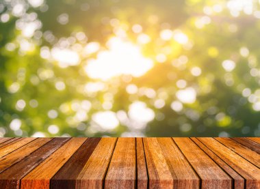 Ahşap masa ve arka plan kullanımı için güneşli yeşil ağaçların bulanık görüntüsü. (Klasik ton))