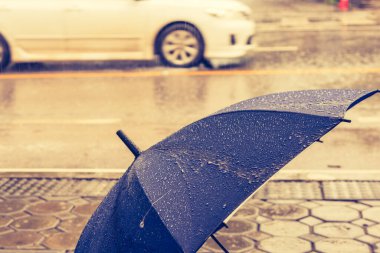 Yolun yakınındaki yağmurda yere konmuş mavi şemsiyenin klasik ton görüntüsü.