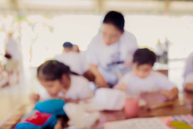 Arka plan kullanımı için parlak güneşli oyun odasında annesiyle resim yapan bulanık çocuk ve anne görüntüsü. .