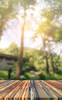 Ahşap masa ve arka plan kullanımı için güneşi olan yeşil ağaç ormanının soyut Bokeh 'inin bulanık görüntüsü. (Klasik ton))