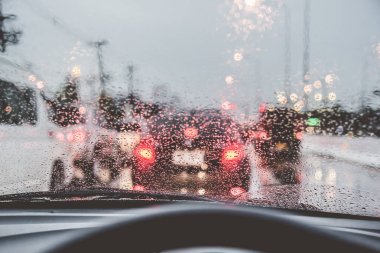 Akşam vakti araba kullanan ve arka planda kullanmak için camlara yağmur damlası konan insanların klasik ton görüntüsü. (içeriden fotoğraf çek)