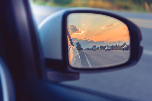 車の翼鏡のヴィンテージトーンのイメージを背景に日没時の後ろの遠近法の道を見る — ストック写真