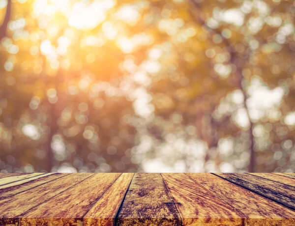 wood table and abstract blur image of green tree bokeh with sun for background usage.(vintage tone)