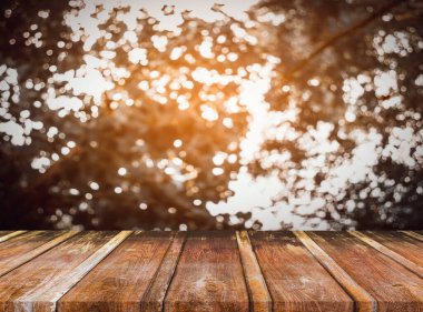 Ahşap masa ve arka plan kullanımı için güneşli yeşil ağaçların bulanık görüntüsü. (Klasik ton))