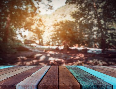 Ahşap masa ve arka plan kullanımı için güneşi olan yeşil ağaç ormanının soyut Bokeh 'inin bulanık görüntüsü. (Klasik ton))