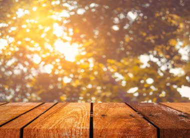 Ahşap masa ve arka plan kullanımı için güneşli yeşil ağaçların bulanık görüntüsü. (Klasik ton))