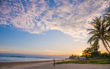 İnsanların soyut bulanık görüntüsü arka plan kullanımı için gün batımı zamanı ile sahilde duruyor .