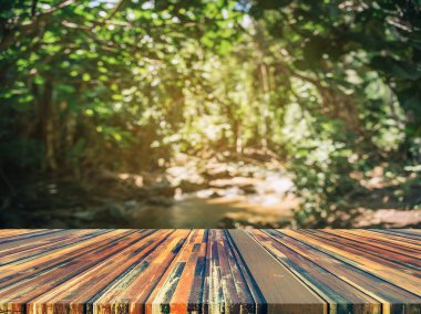 Ahşap masa ve arka plan kullanımı için güneşi olan yeşil ağaç ormanının soyut Bokeh 'inin bulanık görüntüsü. (Klasik ton))