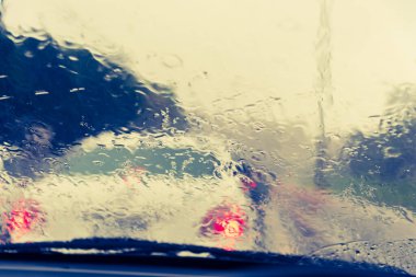 Akşam vakti araba kullanan ve arka planda kullanmak için camlara yağmur damlası konan insanların klasik ton görüntüsü. (içeriden fotoğraf çek)