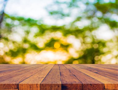 Arkaplan olarak gökyüzü olan ahşap masa ve ormanların bulanık görüntüleri.