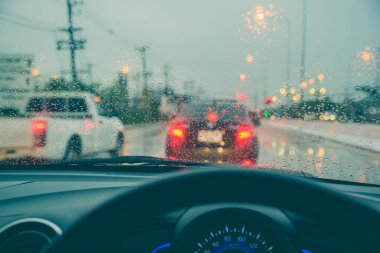 Akşam vakti araba kullanan ve arka planda kullanmak için camlara yağmur damlası konan insanların klasik ton görüntüsü. (içeriden fotoğraf çek)