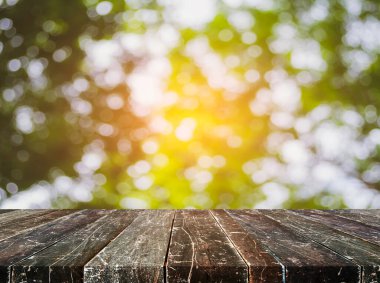 Ahşap masa ve arka plan kullanımı için güneşli yeşil ağaçların bulanık görüntüsü. (Klasik ton))