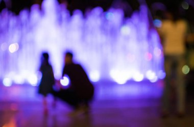 Fıskiyeye gece lambasıyla bakan insanların bulanık arkaplan görüntüsü .