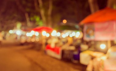 Şenlik ışıklarıyla dekore edilmiş arka plandaki bulanık gece pazarının görüntüsü. (Klasik ton))