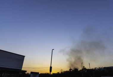 Akşam saatlerinde iş merkezinin otoparkında yanan ormanlardan yükselen dumanla birlikte hava kirliliği var.