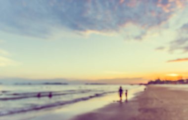 Günbatımında arka plan kullanımı için sahilde duran insanların soyut bulanık görüntüsü. (Klasik ton))