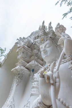 Tayland tapınağındaki beyaz açılı heykelin resmi. (dikey)