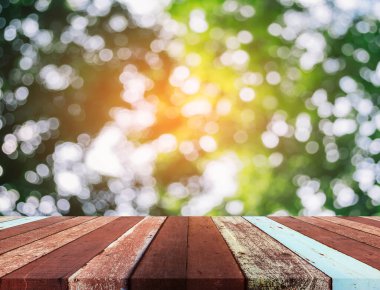Ahşap masa ve arka plan kullanımı için güneşli yeşil ağaçların bulanık görüntüsü. (Klasik ton))