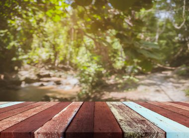 Ahşap masa ve arka plan kullanımı için güneşi olan yeşil ağaç ormanının soyut Bokeh 'inin bulanık görüntüsü. (Klasik ton))