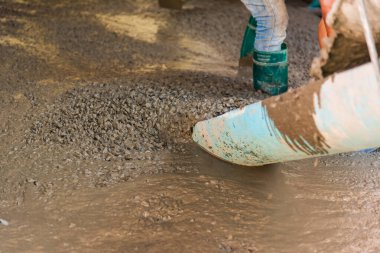 İnşaat alanında zemine beton döken işçilerin görüntüsü.