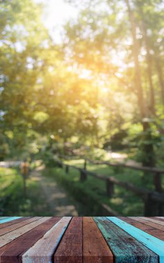 Ahşap masa ve arka plan kullanımı için güneşi olan yeşil ağaç ormanının soyut Bokeh 'inin bulanık görüntüsü. (Klasik ton))