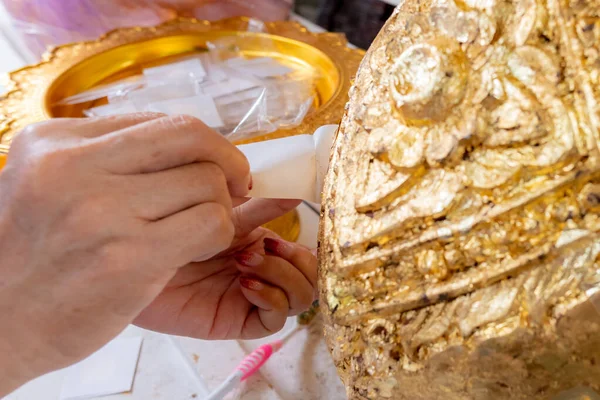 泰国庙宇中手拿金片贴在神圣的金银顶雕像上的特写 — 图库照片